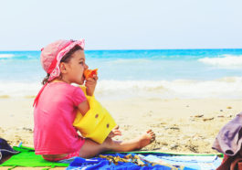 niño comiendo en la playa