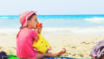 niño comiendo en la playa